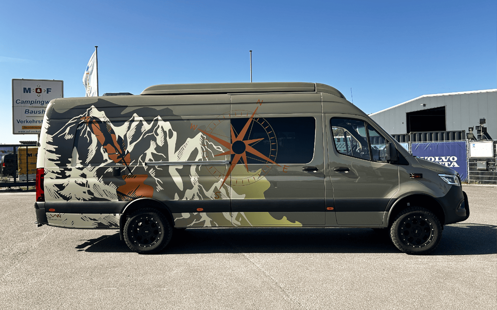 Olivgrüner Mercedes Sprinter mit Grafikfolierung im Freien