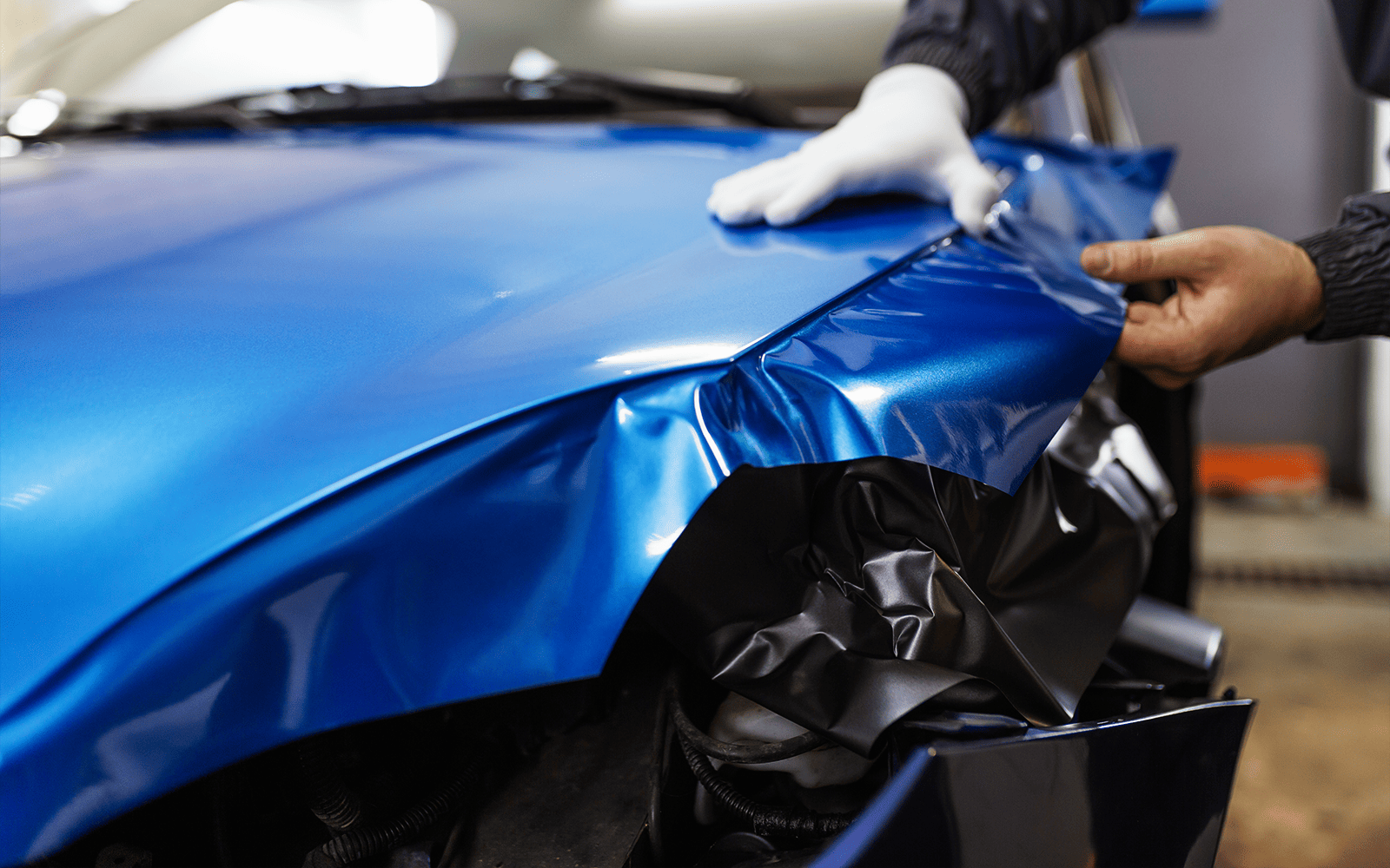 Glänzend blaue Folie wird über die Fahrzeugfront verlegt
